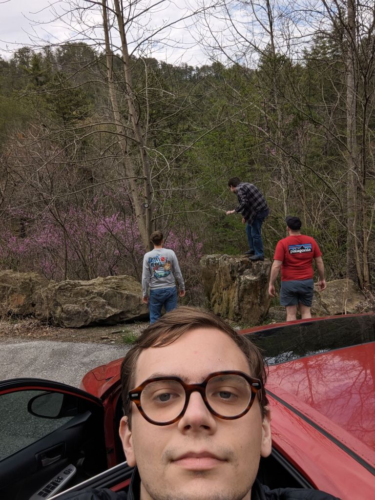Me, and some friends camping, I’m in front of a red car while they look behind me at a valley
